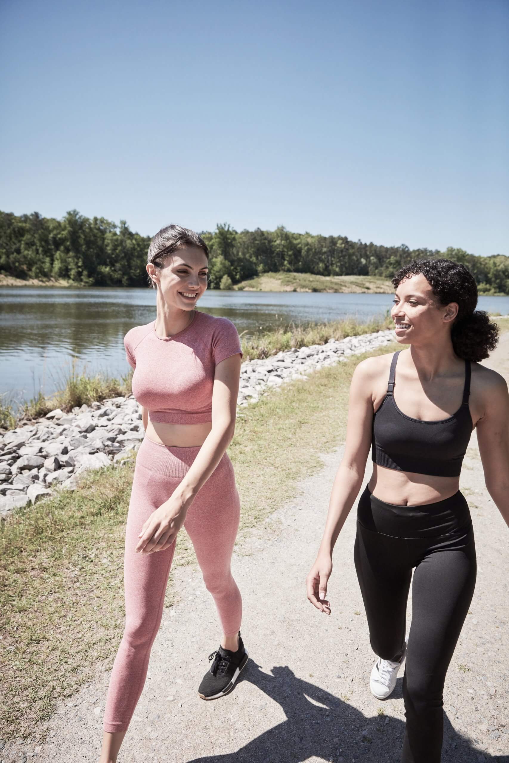 Two women walking on greenway trail by pond